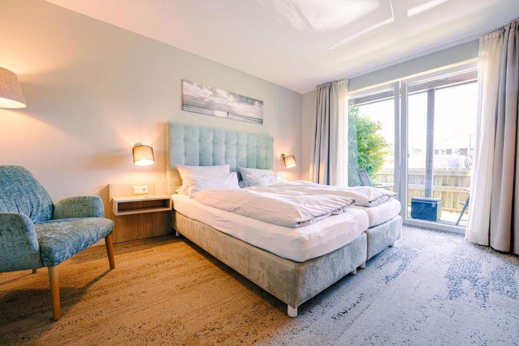 a bedroom with a bed and a chair and a window at Hotel Waastwinj in Utersum