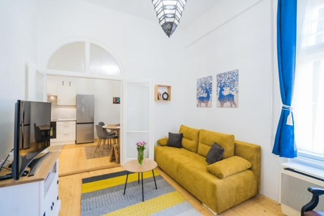 a living room with a yellow couch and a television at Corso Apartman in Siófok