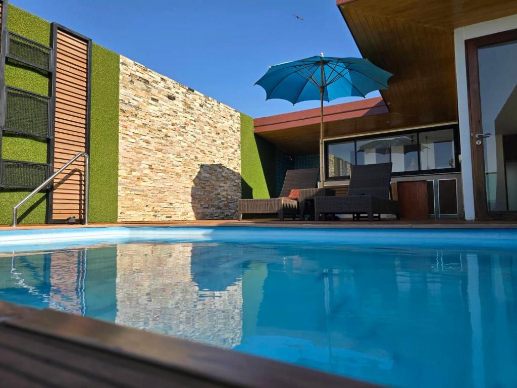 a house with a swimming pool with an umbrella at Blue Sky Private Pool Villa in Chiang Mai