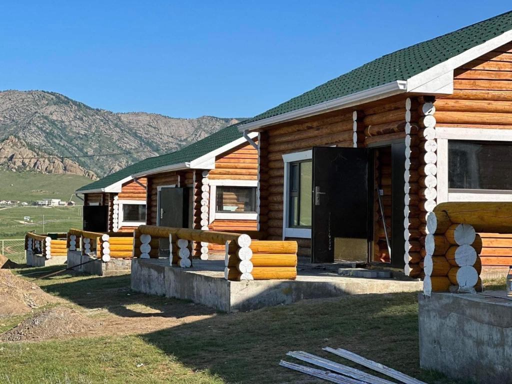 a log cabin with mountains in the background at Terelj Khangai Resort in Belen Hüryee Hiid