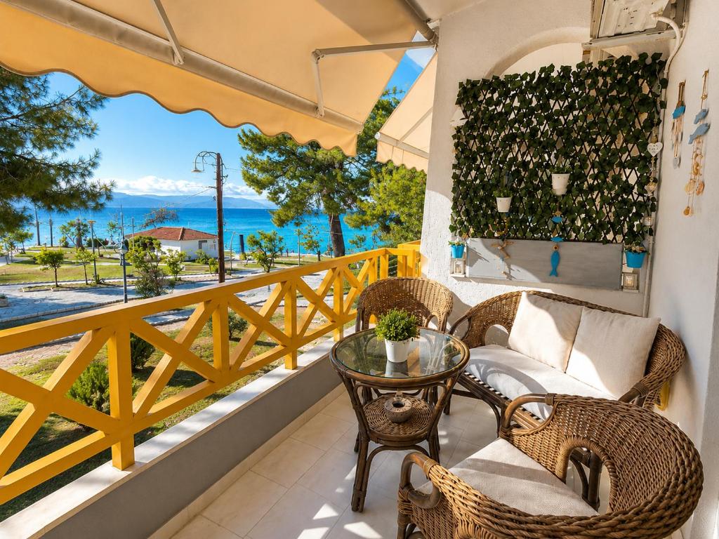 a balcony with a table and chairs and a view of the ocean at Apartment Dolphin Sea View and First Line in Hanioti