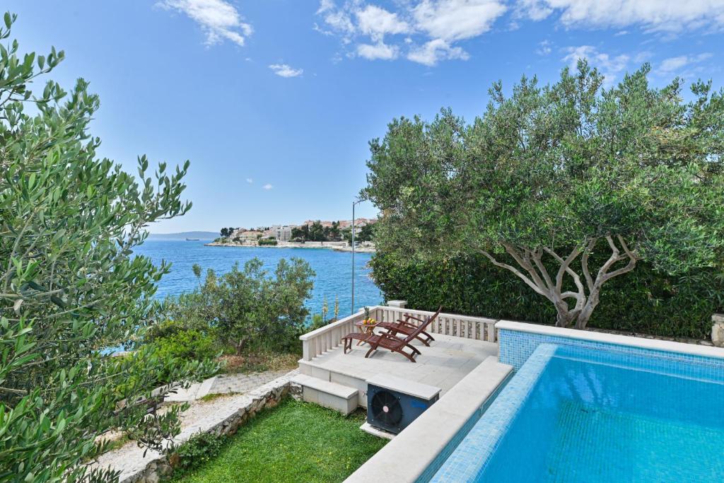 a swimming pool with a bench next to the water at LUXURY VILLA CIOVO Sleeps 17, Infinity Pool, Seafront in Trogir