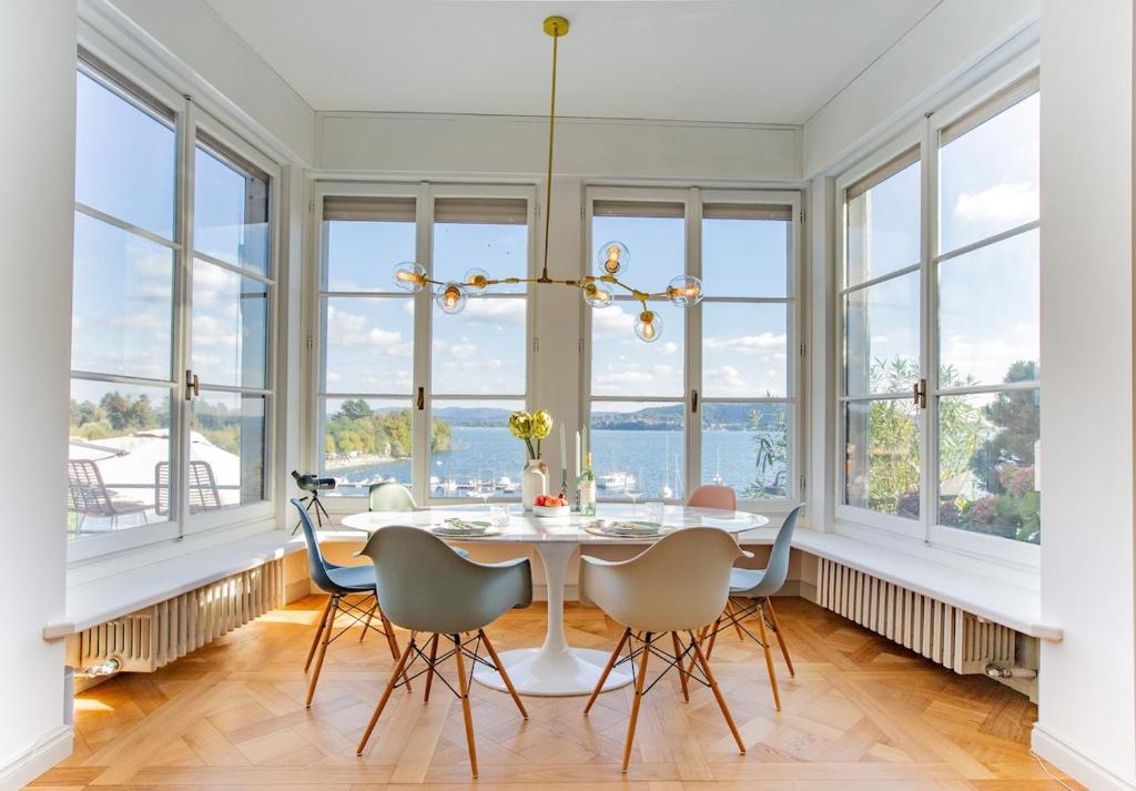 a dining room with a table and chairs and windows at Lake House Lesa - Lakeside Villa Lago Maggiore in Lesa
