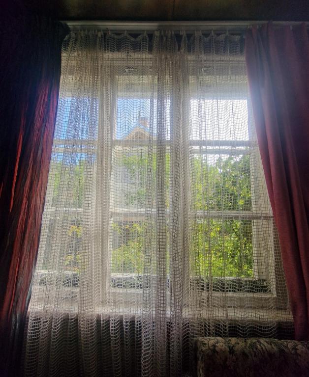 a window with curtains and a view of trees at Bungu Bangu in Ventspils