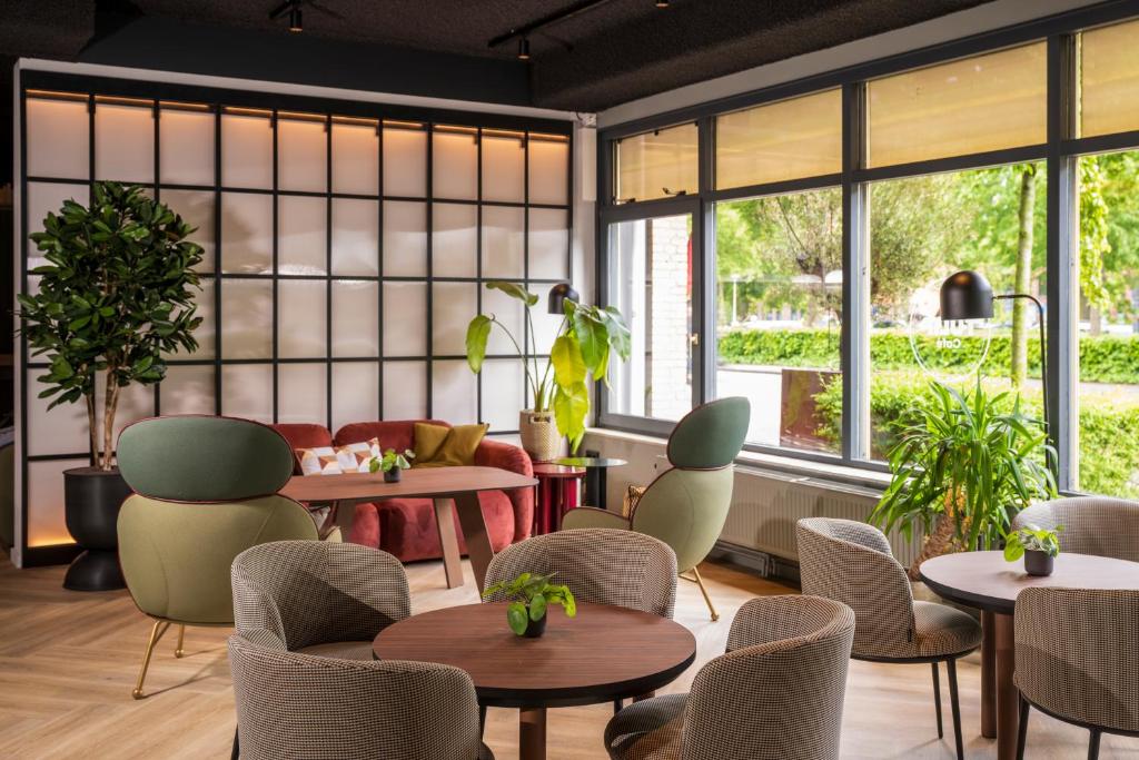 a restaurant with tables and chairs and windows at TULIP Hotels & Residences - Zwolle in Zwolle