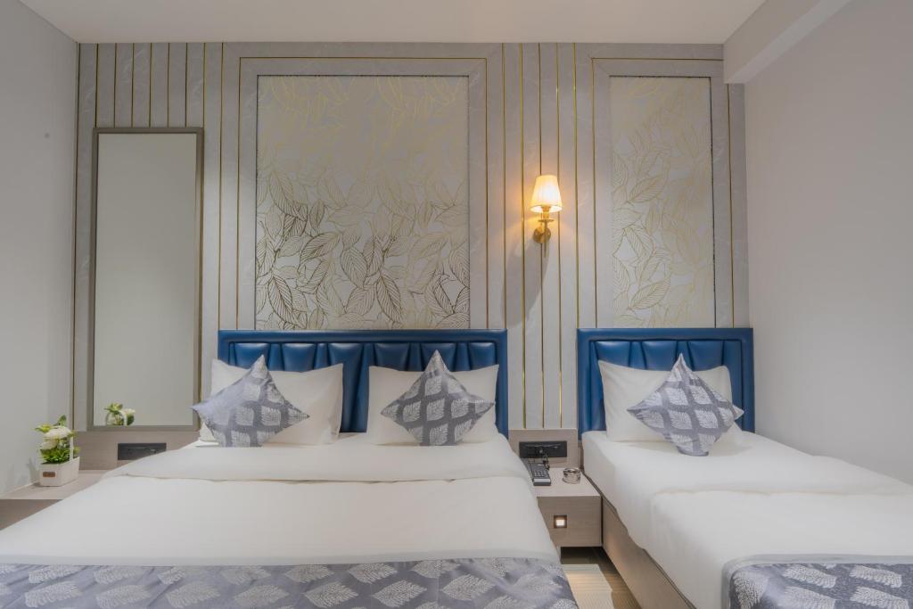 ein Schlafzimmer mit zwei Betten mit blauen und weißen Kissen in der Unterkunft Hotel 7 skye in Surat