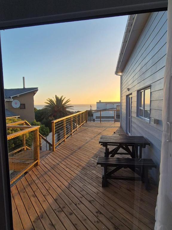 a wooden deck with a picnic table and the ocean at Net Dankbaar in De Kelders