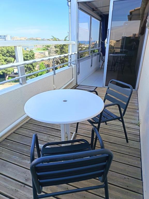 a white table and two chairs on a balcony at studio cabine vue sur mer in Sète