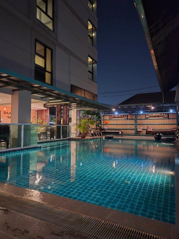 A tiled outdoor pool lit at night beside the hotel building.