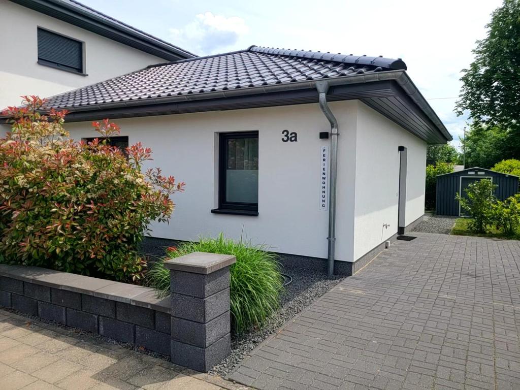 a white house with a black roof at Ferienwohnung Schmidt mit Terrasse in Neustrelitz