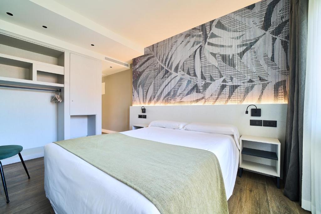a bedroom with a white bed and a painting on the wall at Hostal Sol y Miel in Benalmádena