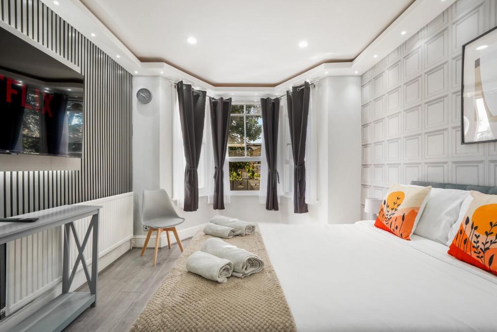 a bedroom with a large white bed and a chair at The Cozy Stays Hackney House in London