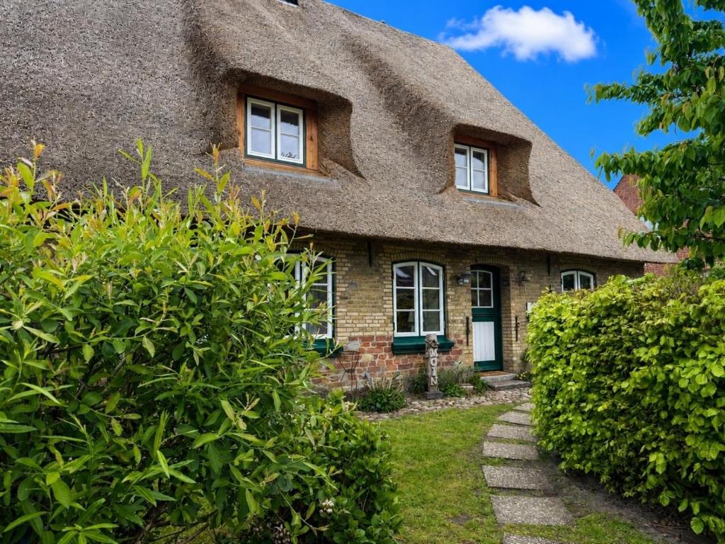 a thatch roofed house with a pathway in front at Reetdachhaus Silvi in Schwabstedt