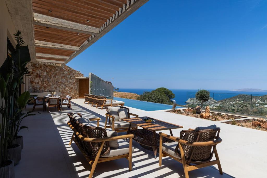 a patio with chairs and tables and a view at Elysium Caved Villas - Carved From Calm by etouri in Heraklio