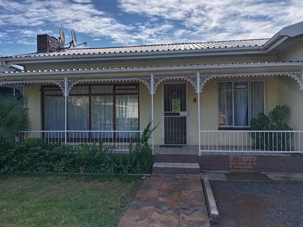 a white house with a porch and a gate at Protea House in Graaff-Reinet