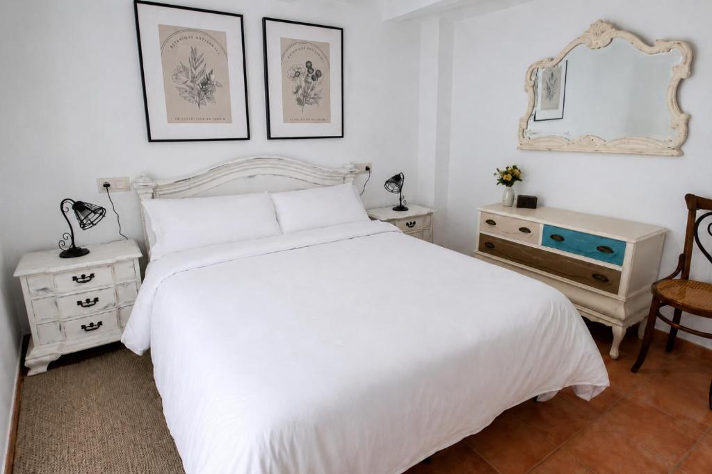 a white bedroom with a white bed and a mirror at La Casonita in Alpuente