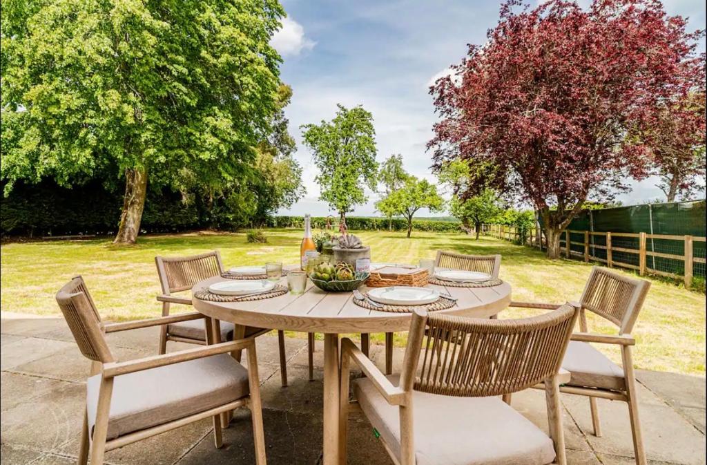 a wooden table with chairs around it in a garden at Dalforth Thaxted Barn Collection in London Stansted Airport
