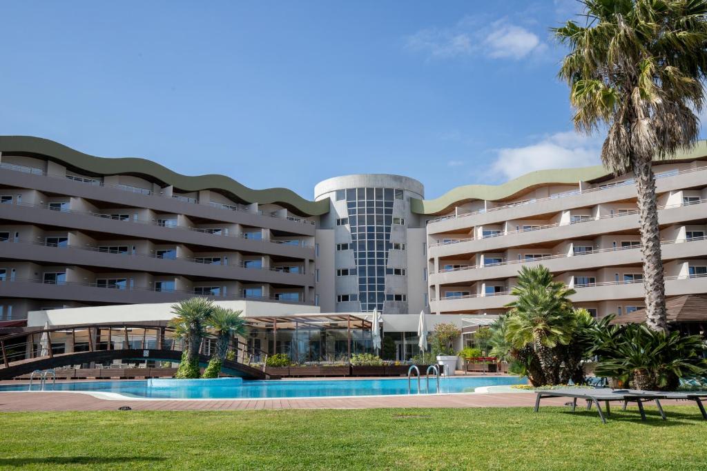 a hotel with a swimming pool and palm trees at MS Aparthotel in Linda-a-Velha