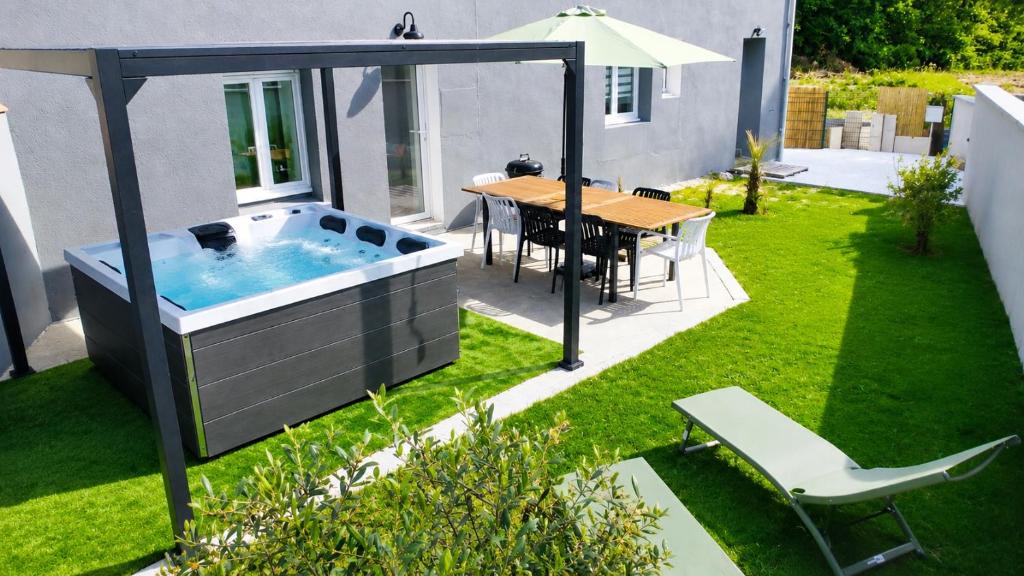 a hot tub in a garden with a table and chairs at Villa Bella & Spa in Mouilleron-le-Captif
