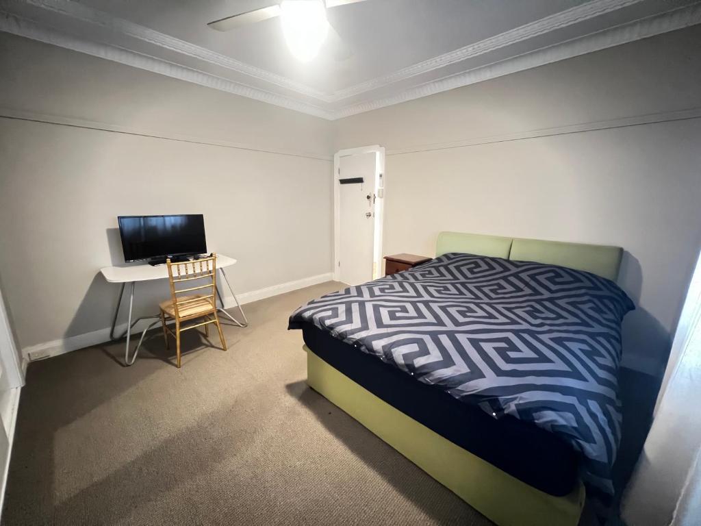 a bedroom with a bed and a desk and a television at Room 73 in Merrylands
