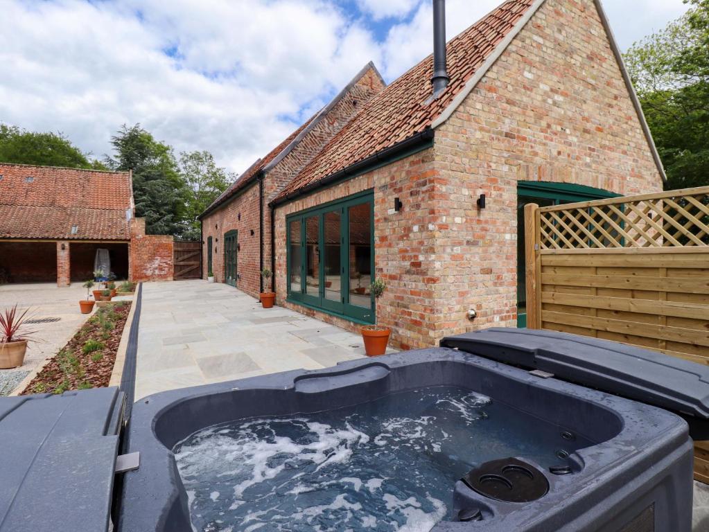 a hot tub in the backyard of a brick building at Bobblehat Barn in Alford