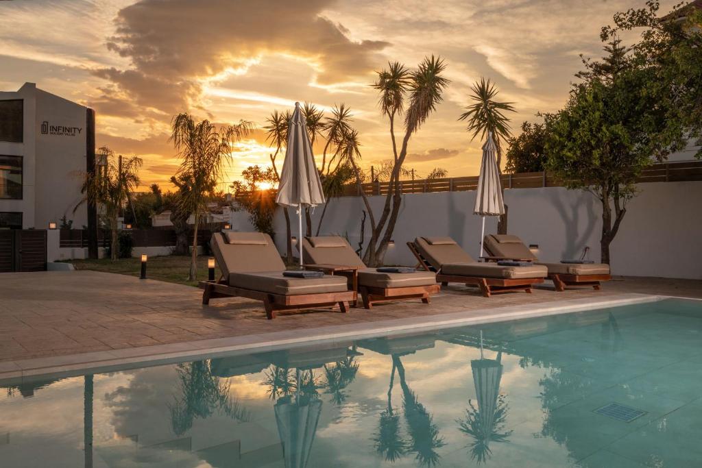 a pool with chairs and umbrellas next to a building at Villa V - Infinity Holiday Villas, For Large Groups With Private Pool, by ZanteWize in Kalamaki