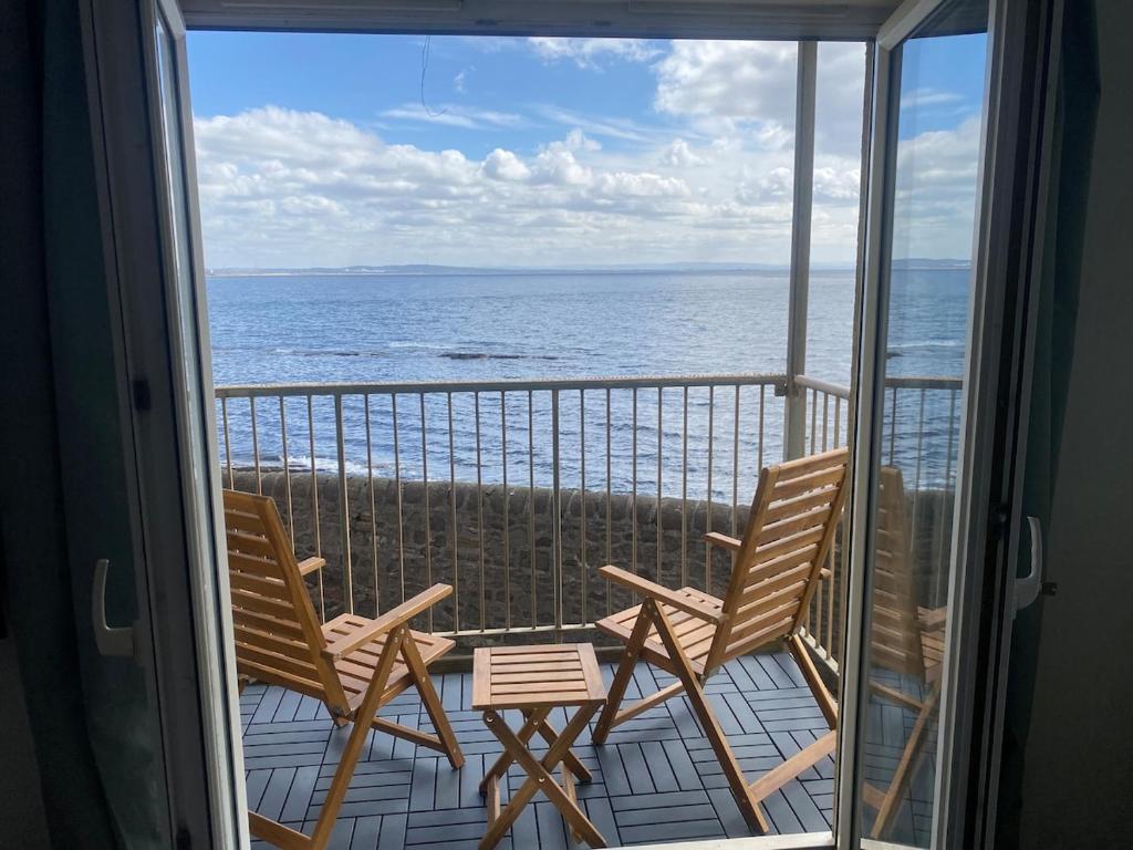 a balcony with two chairs and a view of the ocean at Harbour Point Apartment in Saltcoats