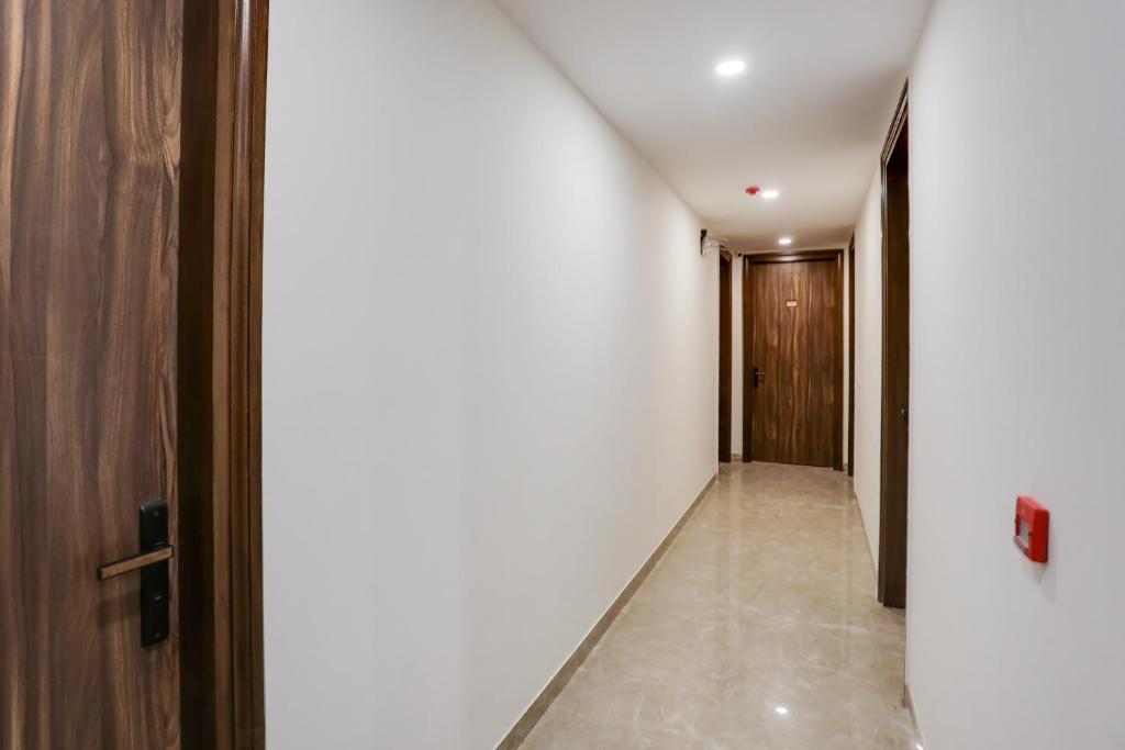 a hallway with white walls and a wooden door at Super Townhouse MA-32 in Gurgaon