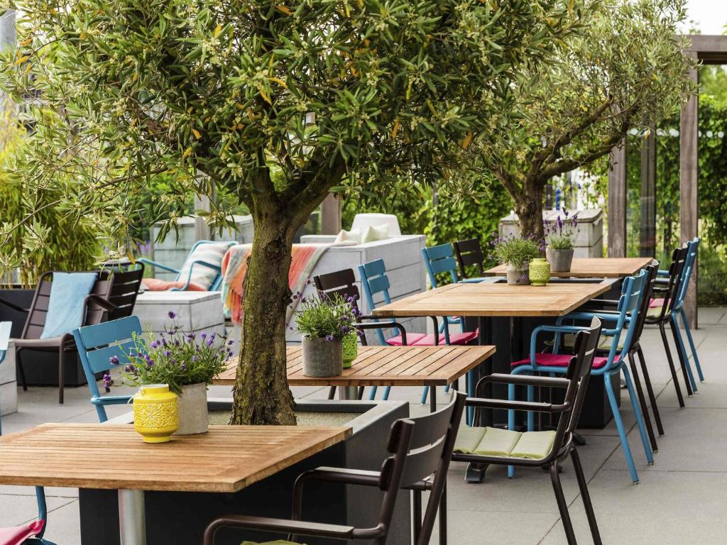 a row of tables and chairs with a tree at Mercure Amsterdam City Hotel in Amsterdam