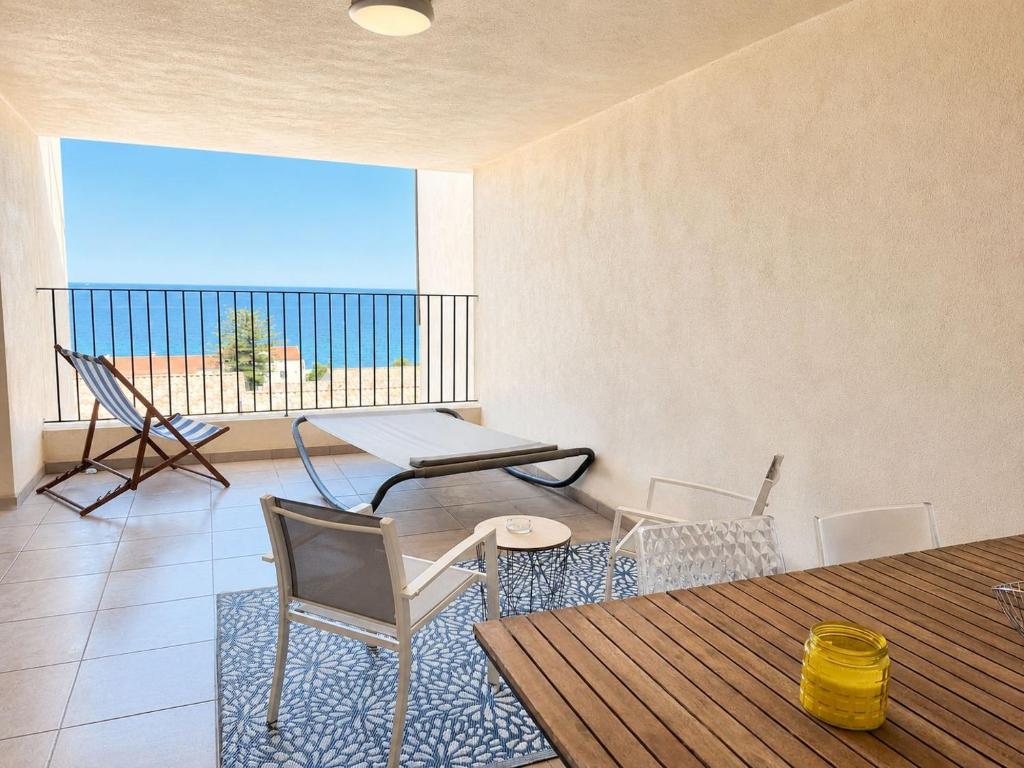 a living room with a table and chairs and a balcony at horizon bleu et détente in Saint-Florent