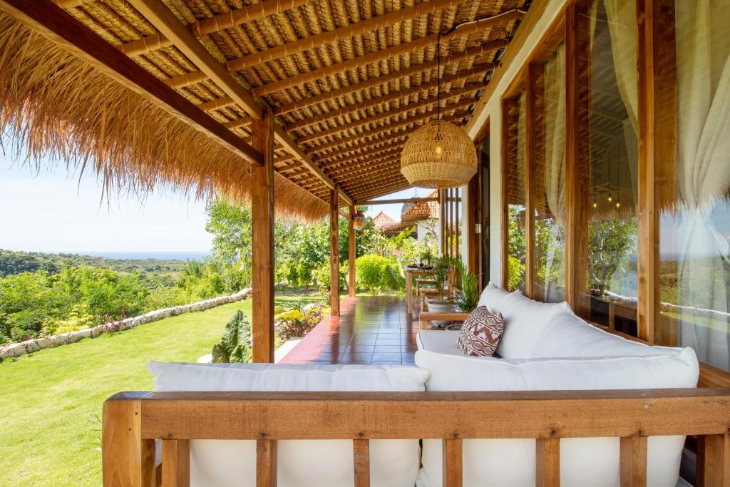 an outdoor patio with white couches on a house at Breath House Penida in Polilit
