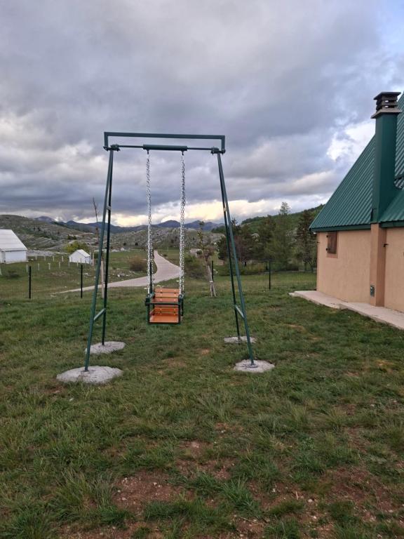 a swing set in a field with a building at VUČJE Ethno House in Nikšić