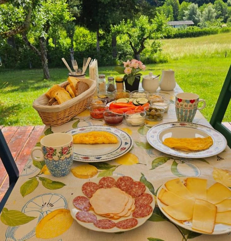 a table with plates of food and a basket of bread at Green Eden in Gornji Zvečaj