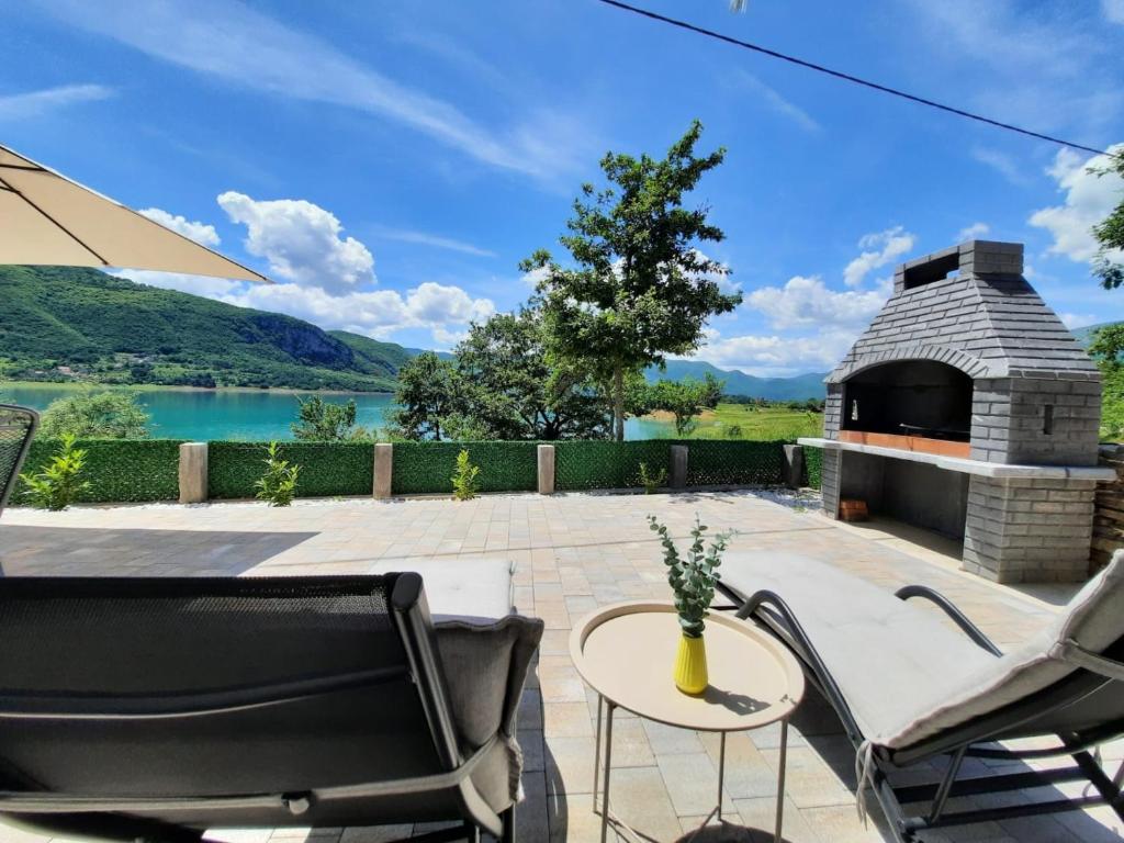 a patio with a fireplace and a table and chairs at Vikendica Dijana Ramsko jezero in Ploča