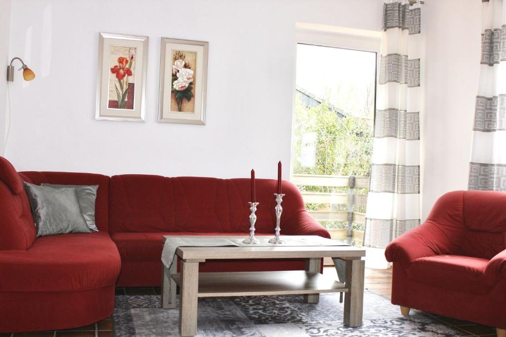 a living room with a red couch and a coffee table at Haus Witten Höhen Ferienwohnungen in Cuxhaven