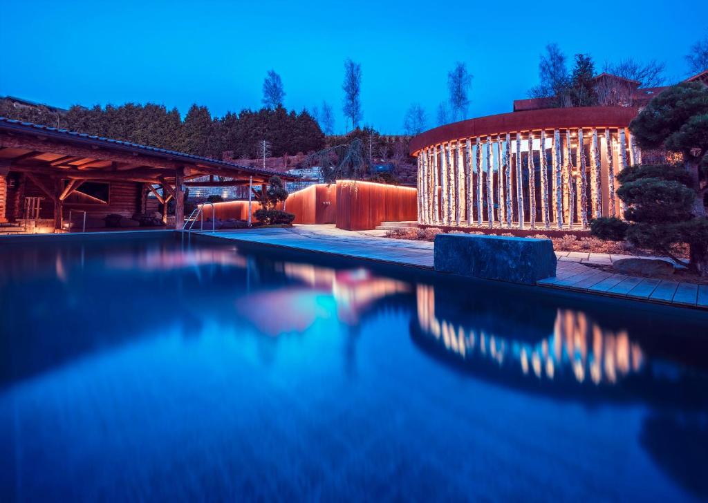 a swimming pool with a building in the background at Hotel MY Kramerwirt in Geiersthal