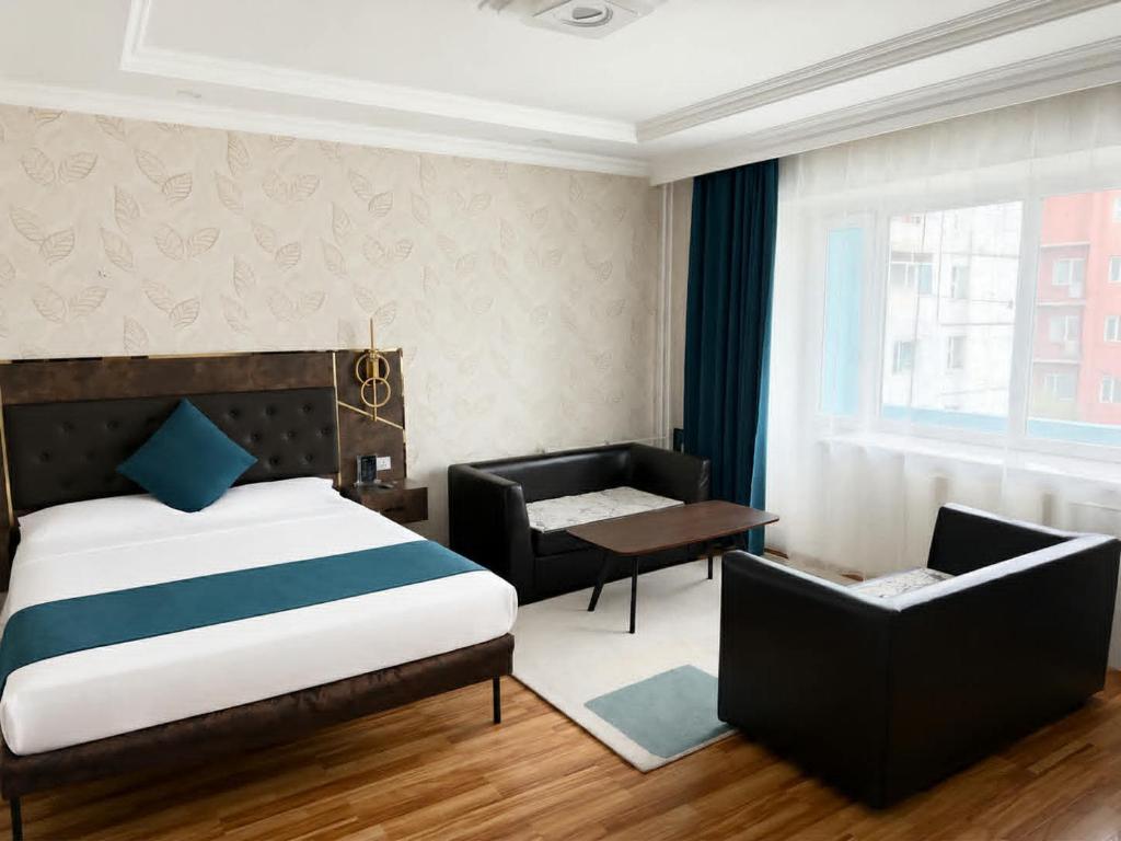 a bedroom with a bed and a chair and a window at Evergreen Hotel in Ulaanbaatar