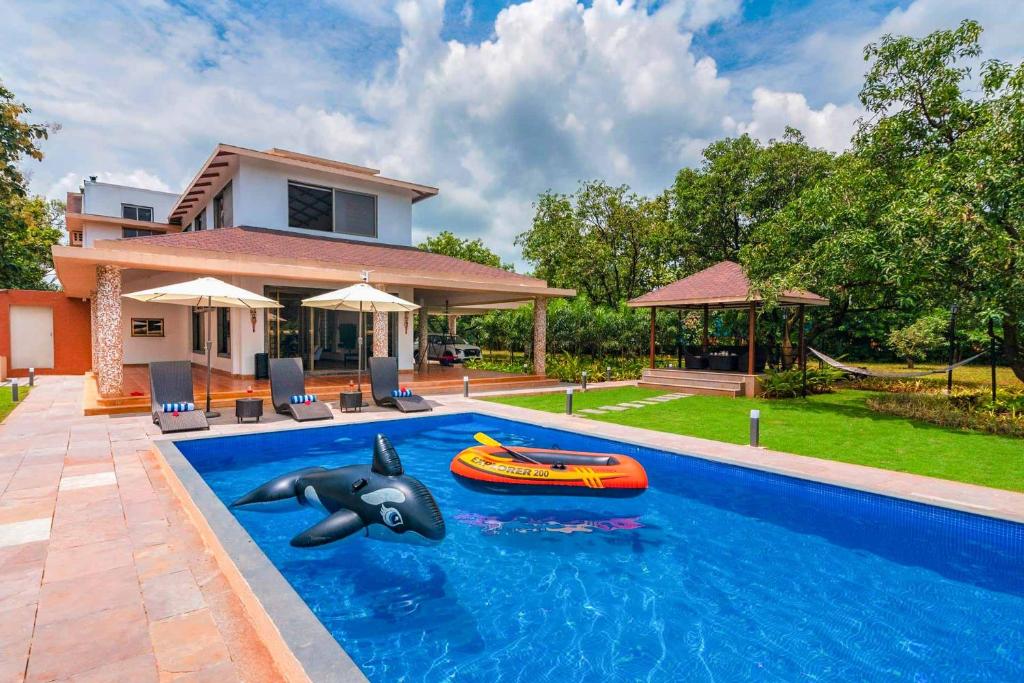 a pool with a inflatable dolphin and an inflatable boat at Classique Woods by StayVista with Lawn with Gazebo & Bar, Indoor Fun in Karjat