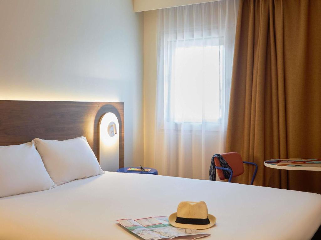 a hat sitting on top of a bed with a window at ibis Avignon Centre Gare in Avignon