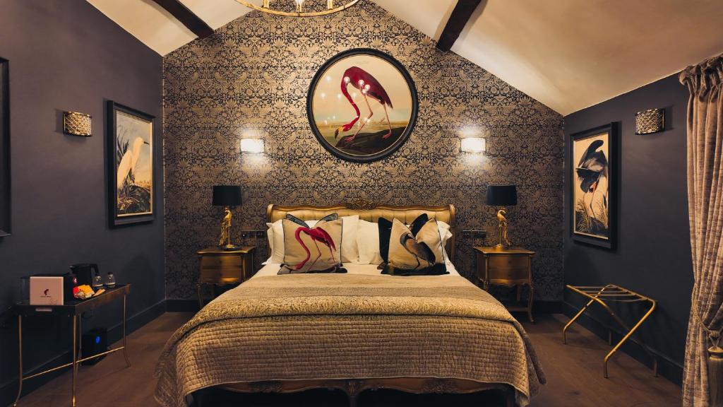 ein Schlafzimmer mit einem Bett und einer Wand mit Gemälden in der Unterkunft Black Rabbit Croston Boutique Hotel & Restaurant in Croston
