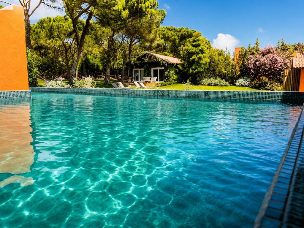 a swimming pool with blue water in front of a house at Quinta da Bicuda in Cascais