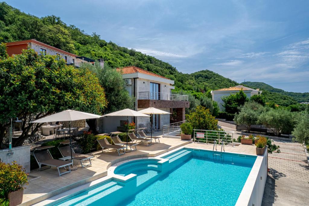 a pool with chairs and umbrellas next to a building at Villa Svinjista in Budva