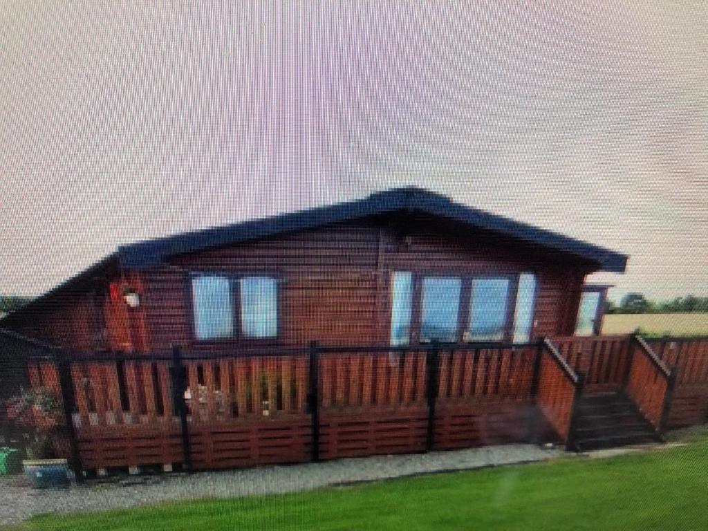 a small log cabin with a wooden deck at ballyskelly lodge in Jemimaville
