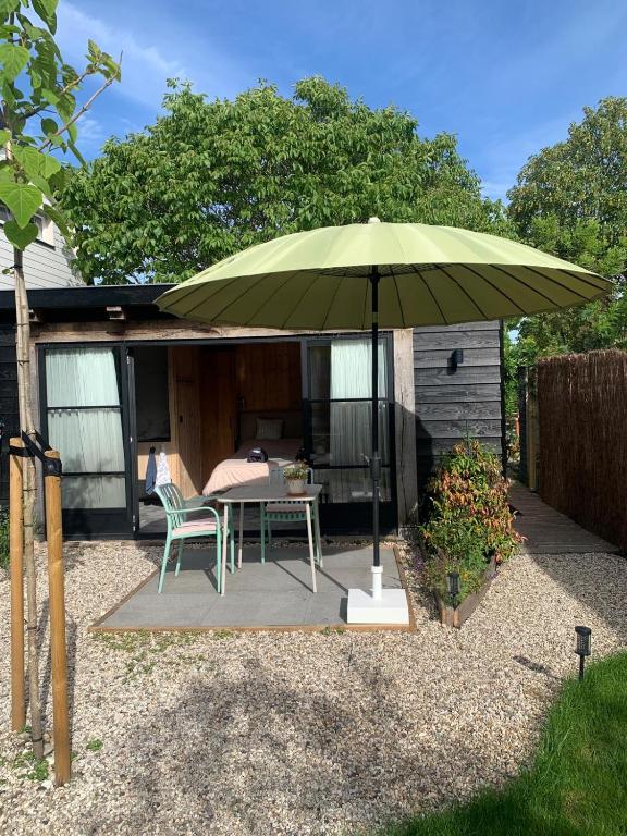 a green umbrella on a patio with a table and chairs at Onder de Oude Walnoot in Sint Pancras