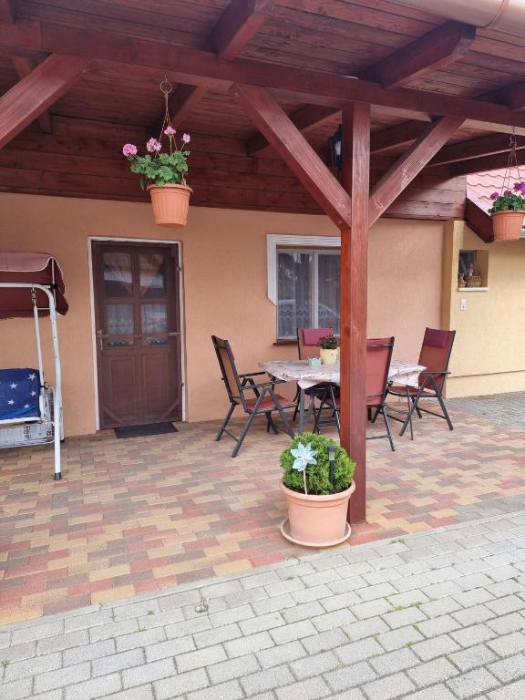 a patio with a table and chairs and a wooden roof at Horváth kuckó in Fonyód