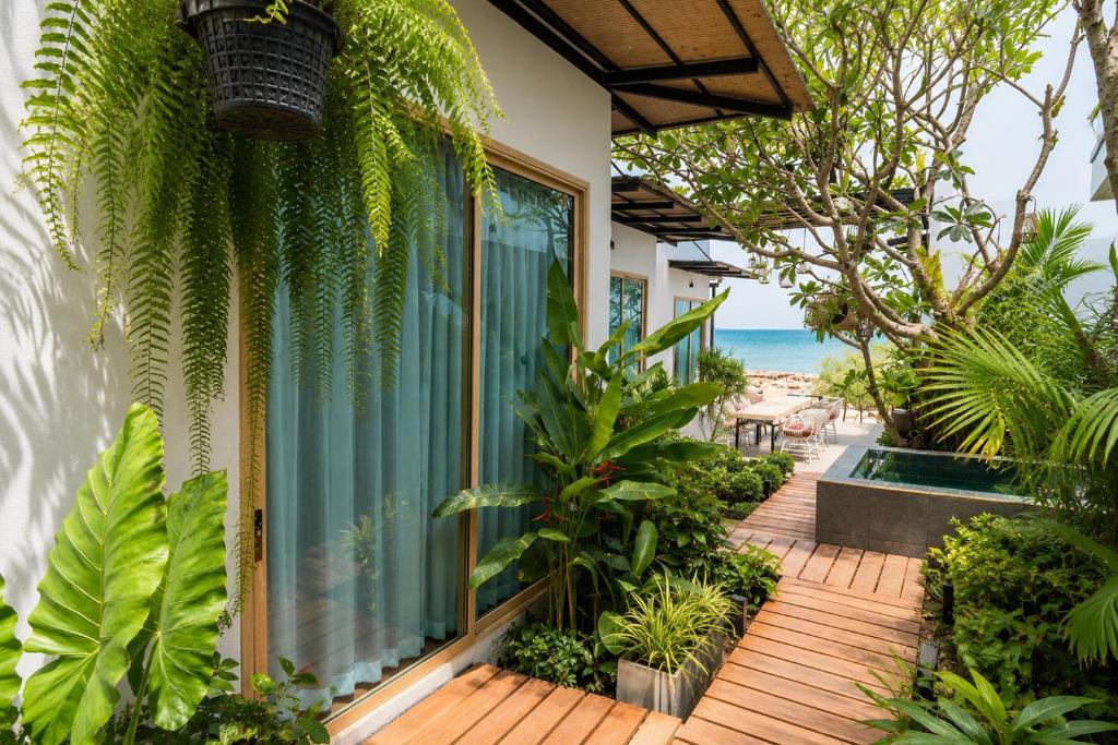 a house with a wooden deck with plants at Ma's Sea Beach House in Klong Muang Beach