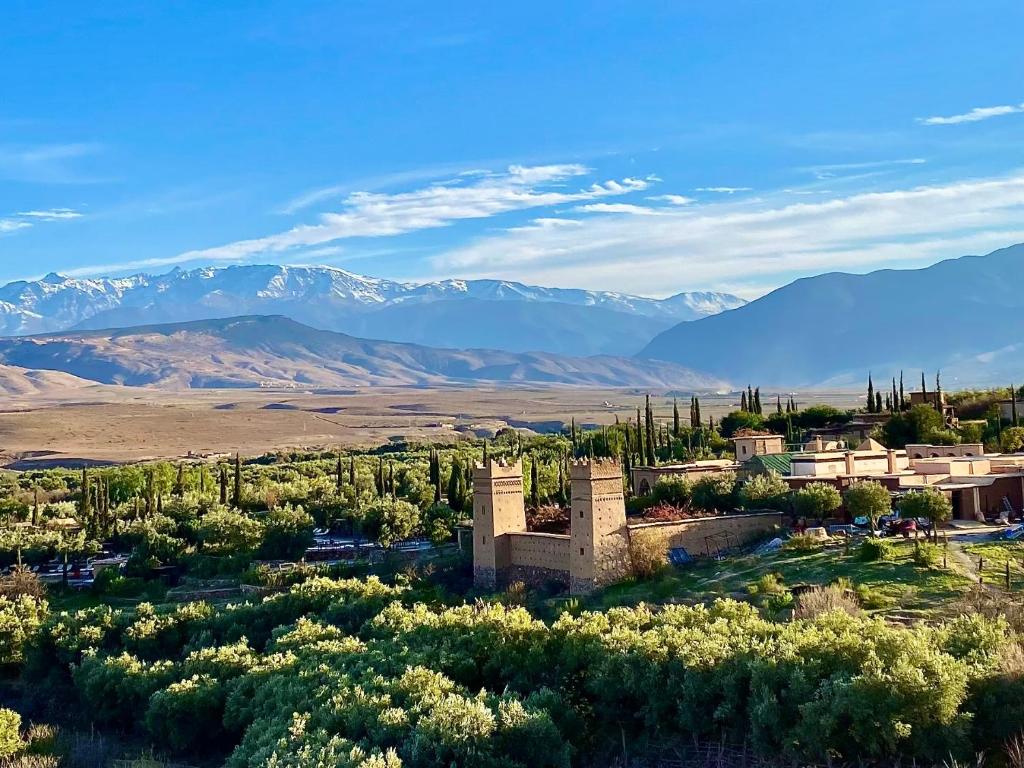an old building in a field with mountains in the background at Kasbah Beldi in Lalla Takerkoust