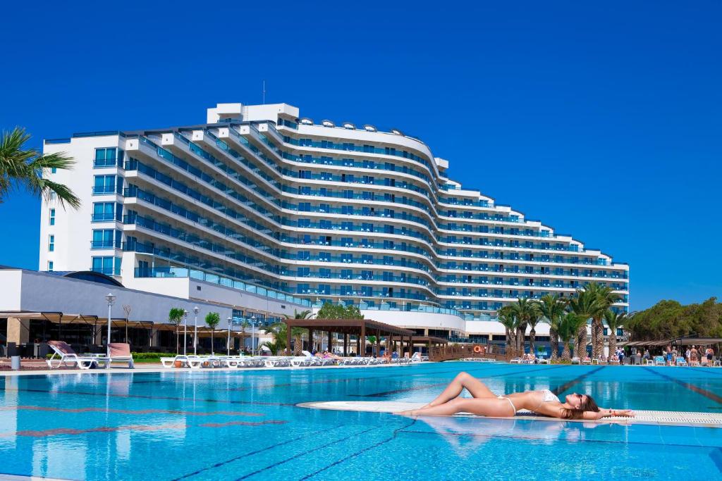 una mujer tumbada en una piscina frente a un hotel en Venosa Beach Resort & Spa - All Inclusive, en Didim
