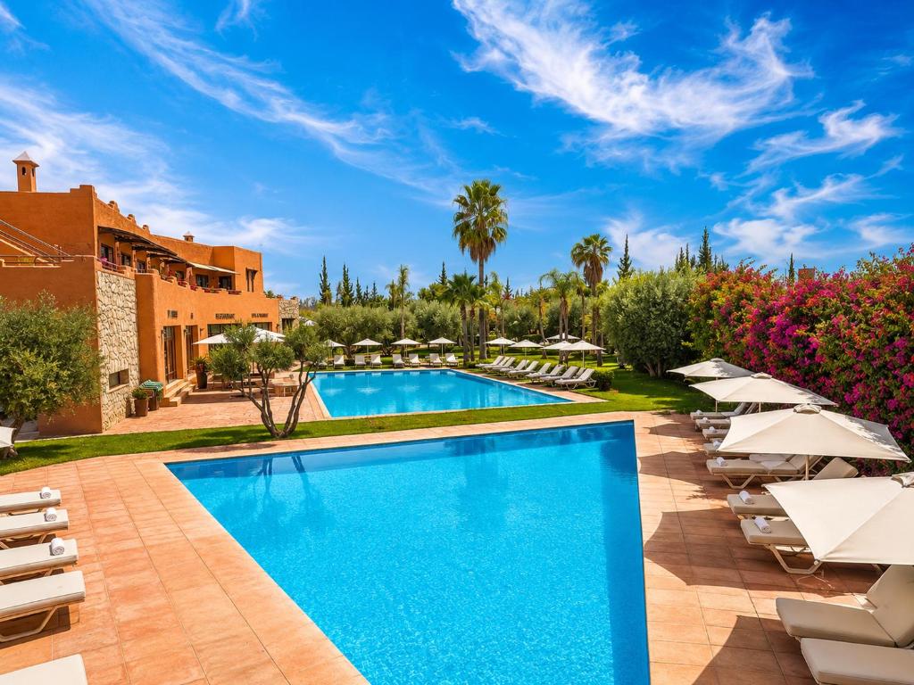 a pool at a resort with lounge chairs and umbrellas at Ourika Camp Suites Hotel & Resort in Marrakesh