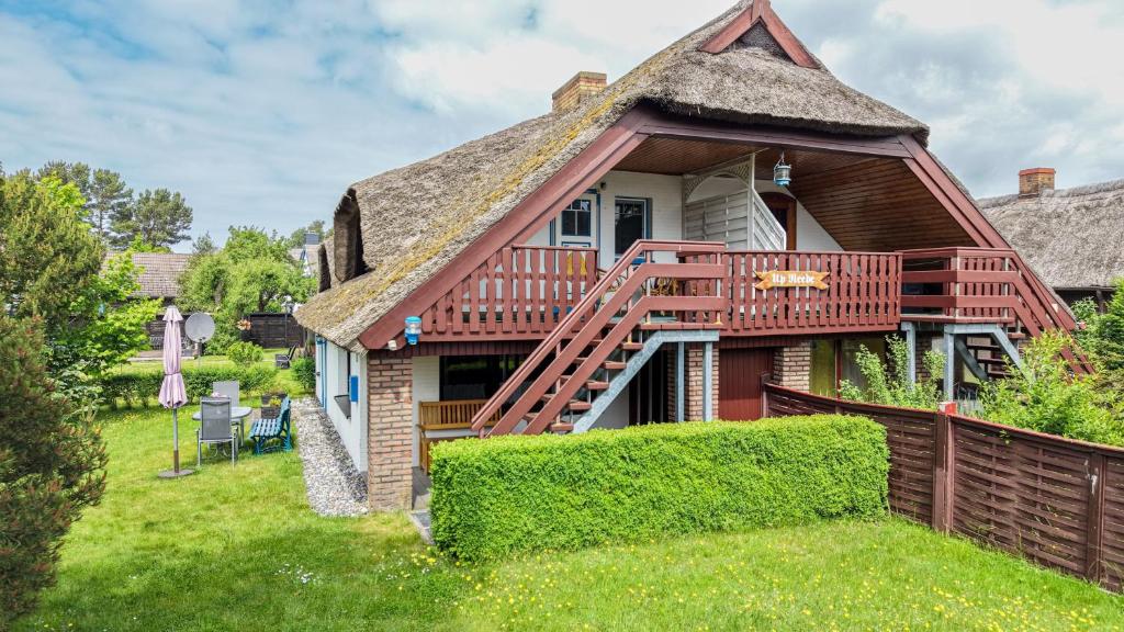 a house with a thatched roof and a deck at Haus Ottomar in Wieck